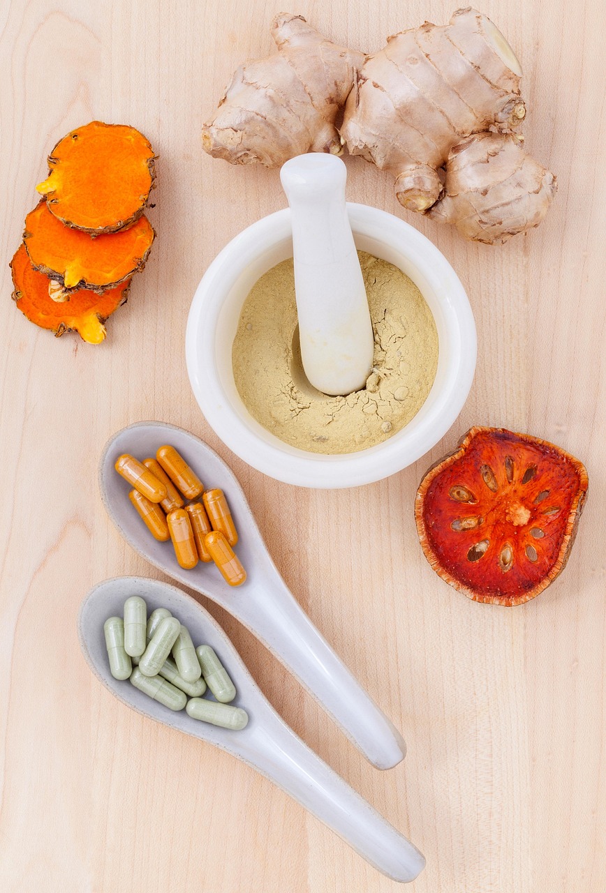 Turmeric, ginger and herbal capsules beside a mortar and pestle